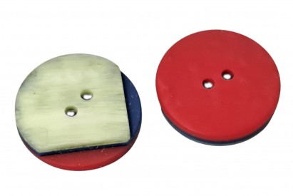 Een groen/blauw/rode kunststof knoop  Doorsnee ongeveer 20 mm.  Met 2 gaten