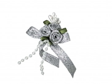 Een opnaaibare corsage van strikje met 3 roosjes, blaadjes en kraaltjes  Zilverkleurig  Ongeveer 5 x 6 cm.  Ook voor decoratie