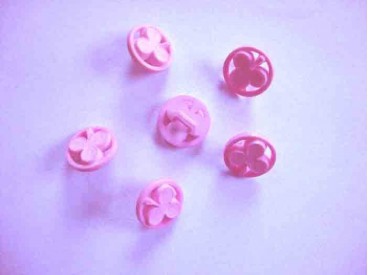 Een roze kunststof knoop met een klaver afbeelding. Doorsnee 13 mm.