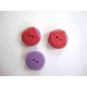 Een rood/groen/paarse kunststof knoop met een doorsnee van 20 mm.